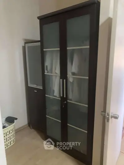 Spacious storage area with elegant glass-door wardrobe in modern apartment.