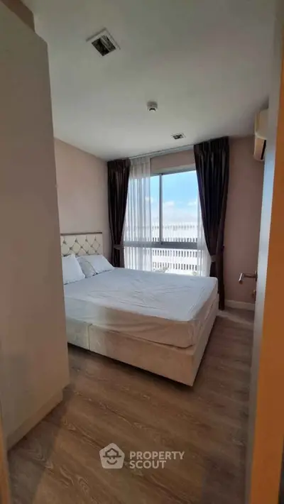 Spacious bedroom with large window offering stunning views and natural light, featuring elegant decor and cozy ambiance.