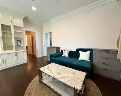 Elegant living room with dark wood flooring, teal sofa, and marble coffee table