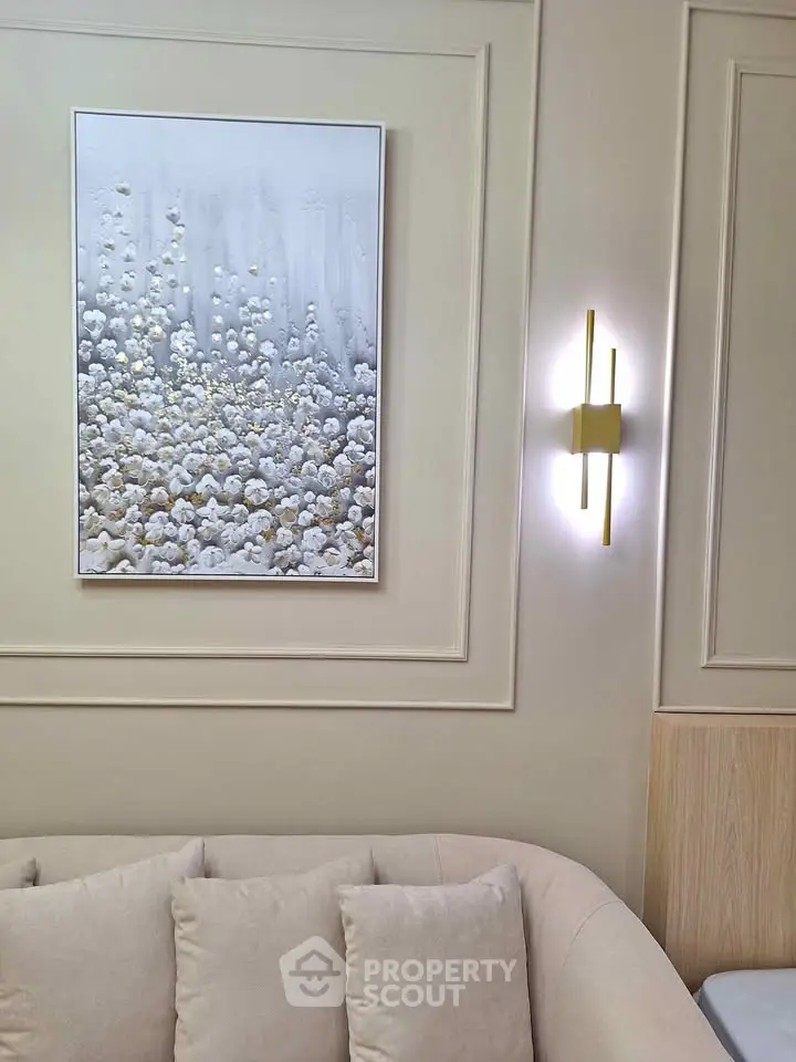 Elegant living room with modern art and stylish lighting, featuring a plush beige sofa and sophisticated wall decor.