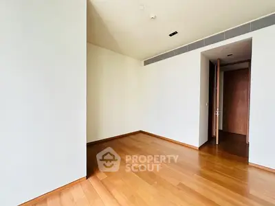 Spacious empty room with wooden flooring and open door, ideal for customization.