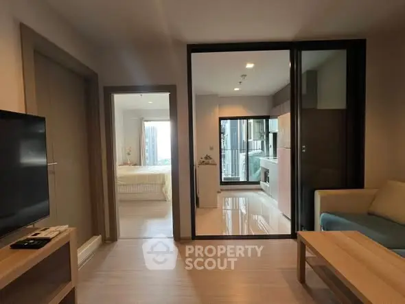 Modern apartment interior with open layout connecting living room, kitchen, and bedroom.