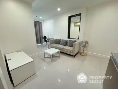 Spacious and modern living room with glossy tiled flooring, comfortable sofa set, and a large mirror adding depth and elegance.