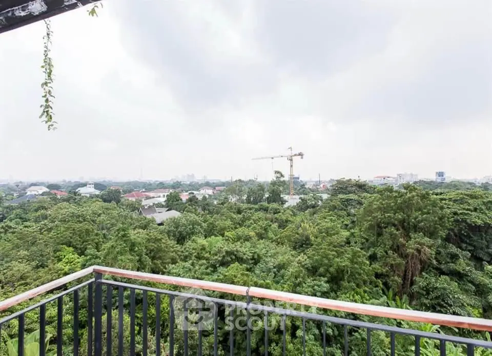 Stunning panoramic view from a balcony overlooking lush greenery and city skyline.