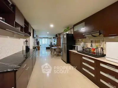 Spacious modern kitchen with sleek cabinetry and open layout leading to dining area.