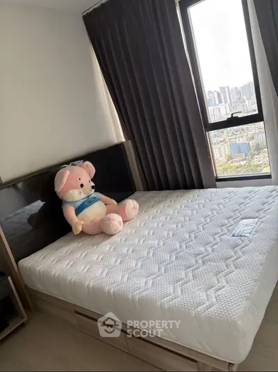 Cozy bedroom with city view, featuring a plush teddy bear on a comfortable bed.