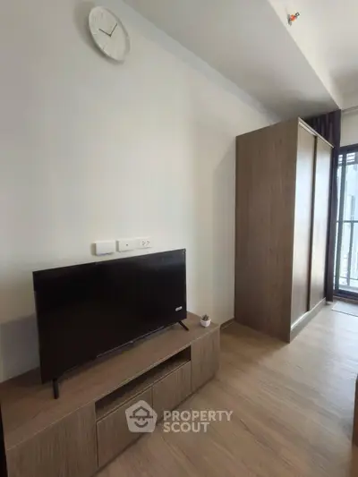 Modern living room with sleek TV stand and large wardrobe, featuring minimalist design and natural light.