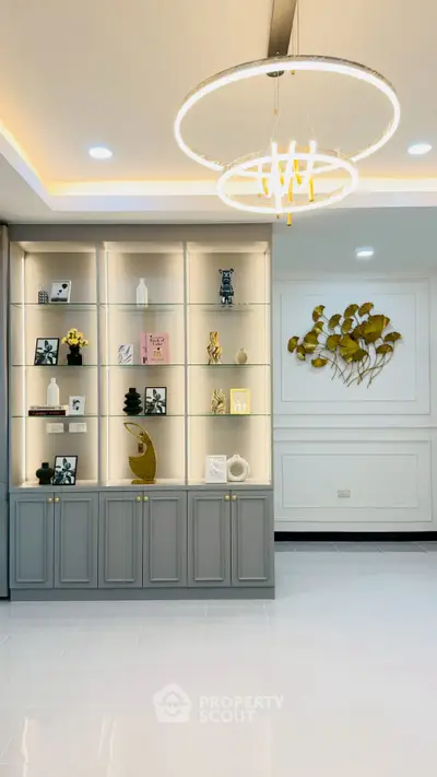 Elegant living room with modern chandelier and stylish shelving unit, perfect for contemporary home decor.