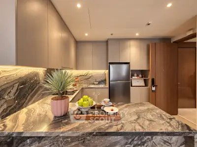Luxurious modern kitchen with marble countertops and sleek cabinetry, featuring a stainless steel fridge and elegant decor.