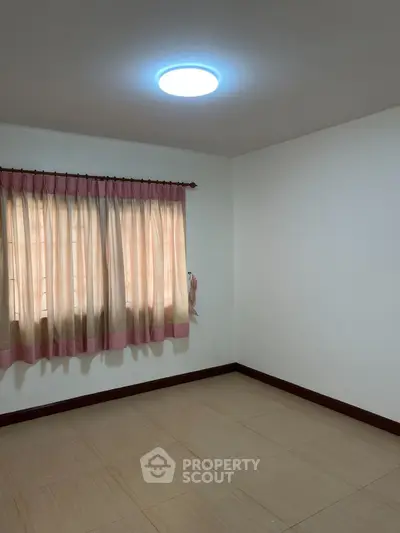 Spacious empty room with tiled flooring and large window with curtains, ideal for customization.