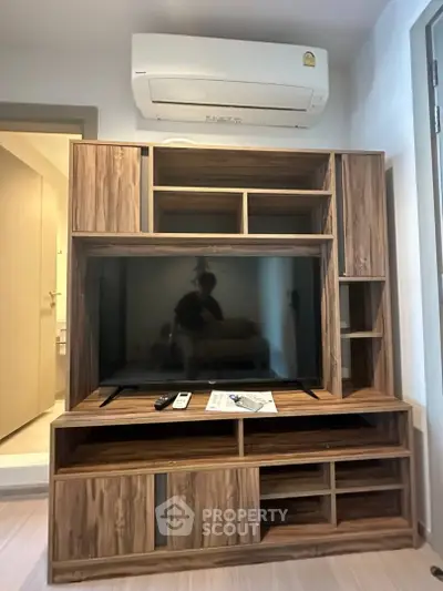 Modern living room with stylish wooden TV cabinet and air conditioning unit.