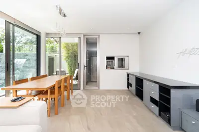 Modern dining area with sleek furniture and large windows offering natural light.