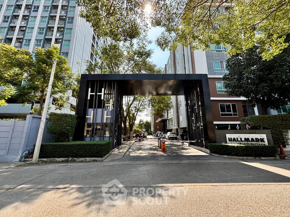 Modern apartment building entrance with lush greenery and sleek design.