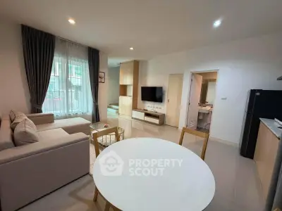 Modern living room with open kitchen, featuring sleek furniture and natural light.