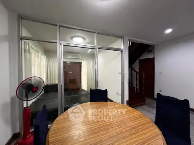 Spacious interior with round wooden table and glass partition, ideal for modern living.