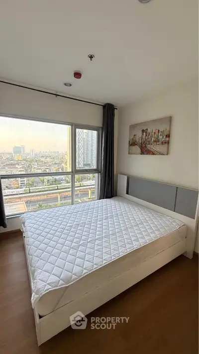 Spacious bedroom with large window offering city views, featuring a modern bed and stylish decor.
