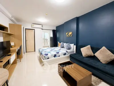 Modern studio apartment with stylish decor and cozy furnishings, featuring a comfortable bed and a sleek sofa.