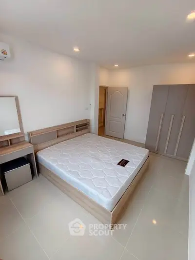 Spacious bedroom with modern wooden furniture and ample natural light.