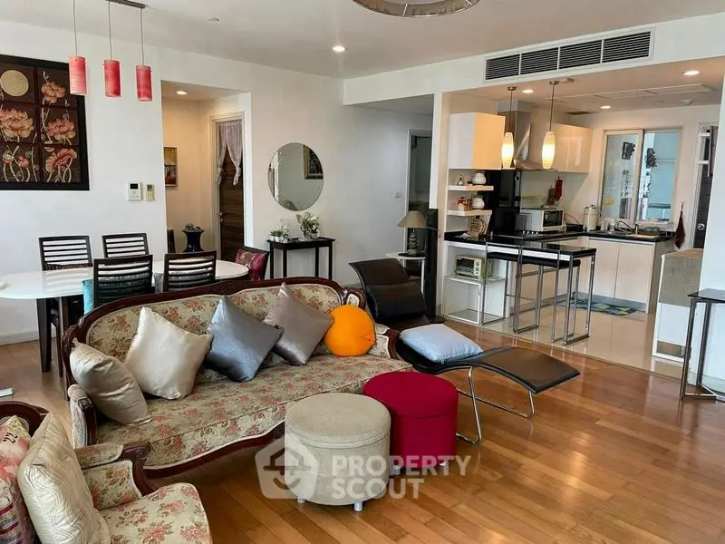 Spacious living room with elegant decor and open kitchen layout, featuring hardwood floors and modern furnishings.