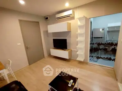 Modern living room with sleek design and open kitchen layout, featuring wall-mounted TV and air conditioning.