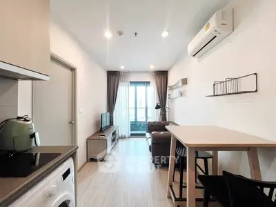 Modern living room with stylish furniture and natural light, featuring a compact kitchen area.