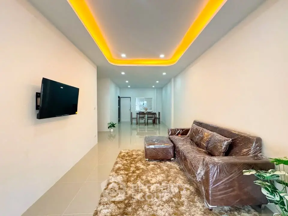 Modern living room with stylish ceiling lights, plush sofa, and wall-mounted TV in a spacious open layout.