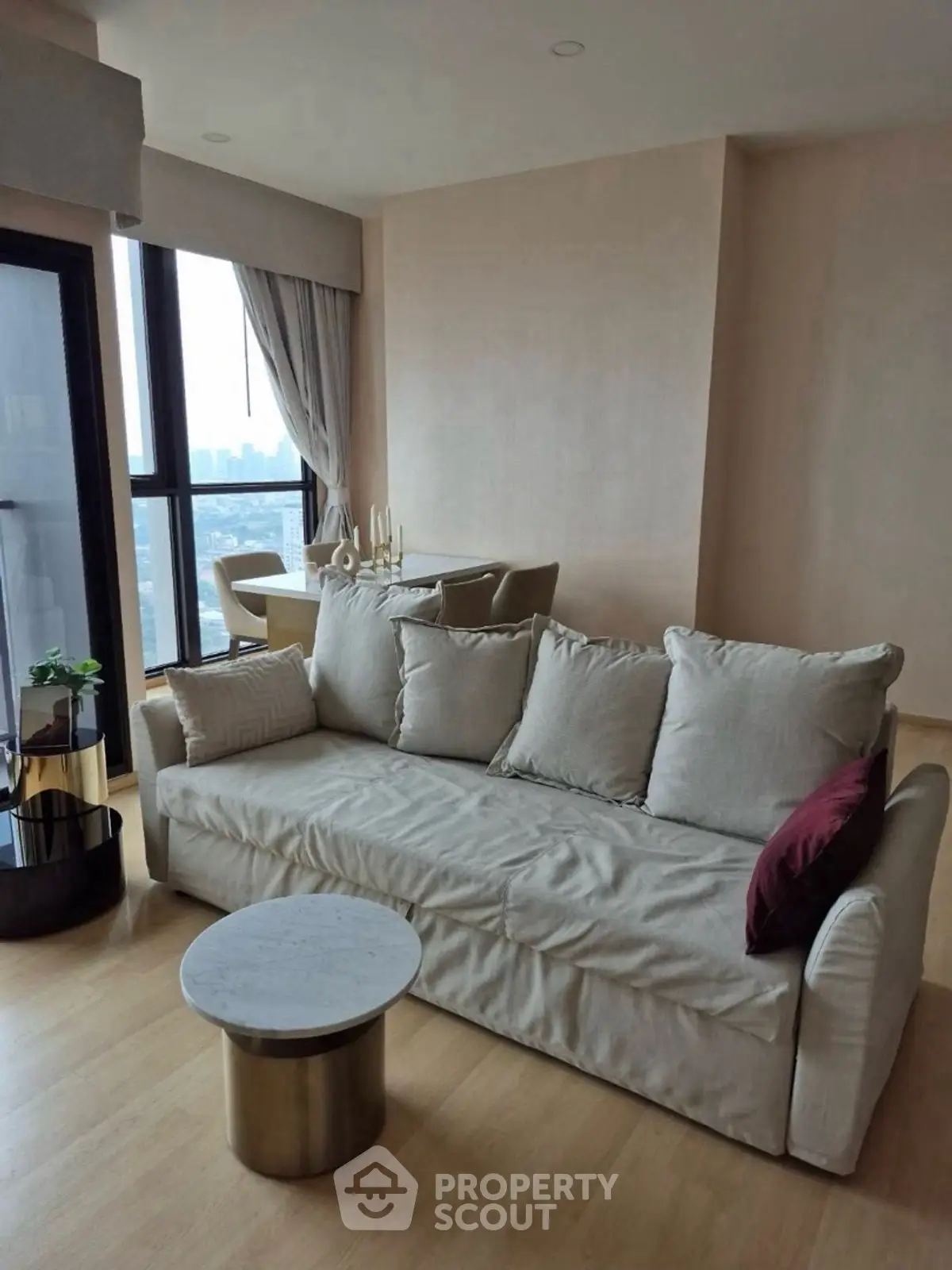 Modern living room with cozy sofa and city view from large windows.