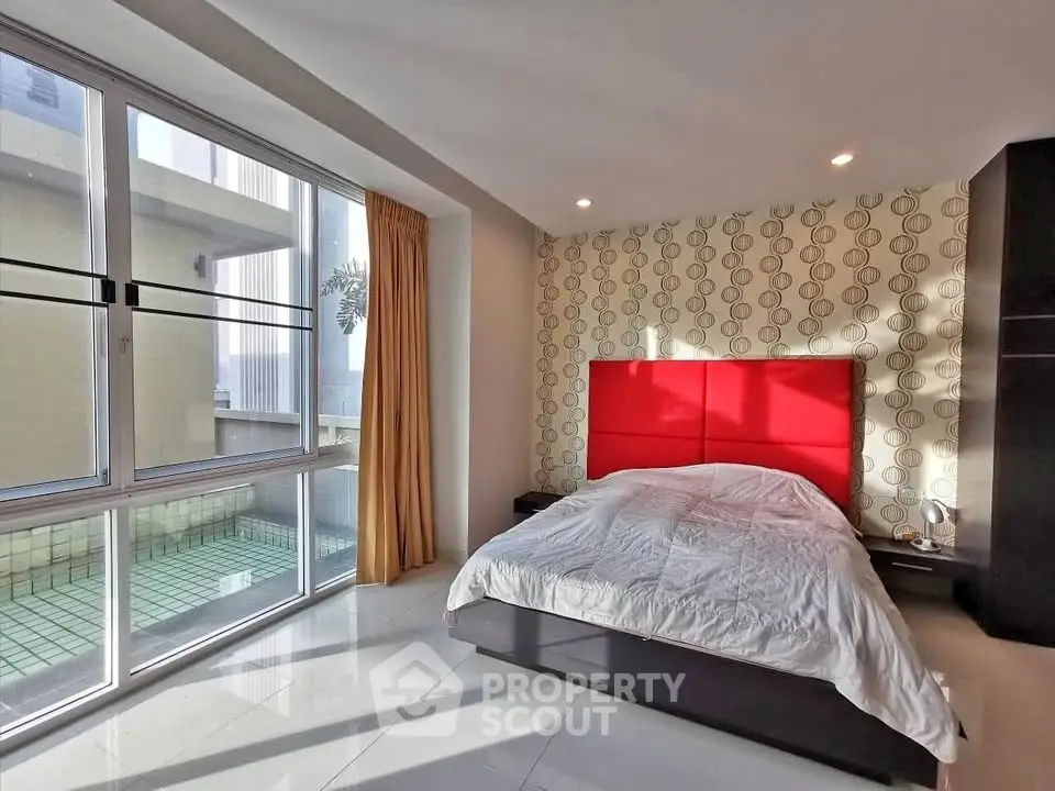 Spacious bedroom with modern decor and large windows offering natural light.