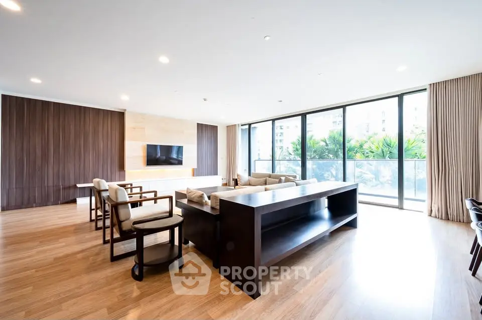Spacious modern living room with large windows and elegant wooden flooring.