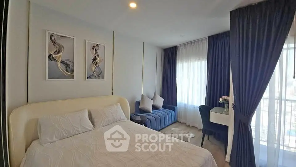 Elegant bedroom with modern decor, cozy seating area, and large windows with dark curtains.