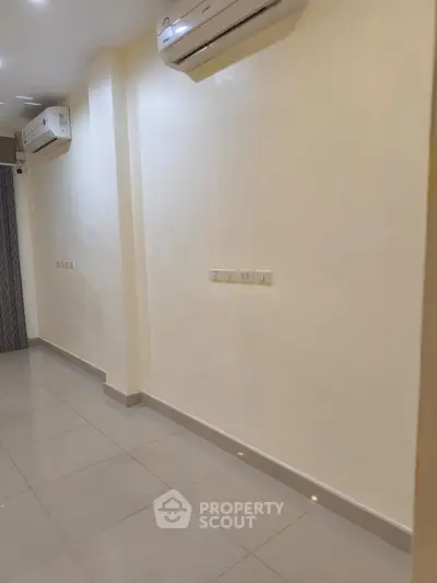 Spacious empty room with tiled floor and air conditioning units, ideal for customization.