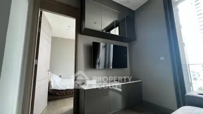 Modern living room with sleek TV setup and view into a cozy bedroom