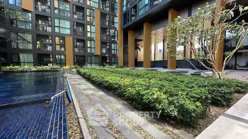 Modern apartment complex with pool and lush garden landscaping