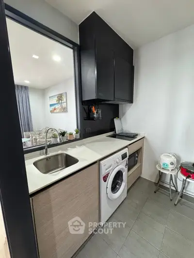 Modern kitchen with washing machine and sleek cabinetry in a stylish apartment