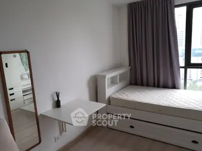 Cozy bedroom with single bed, wall-mounted table, and large window with city view.