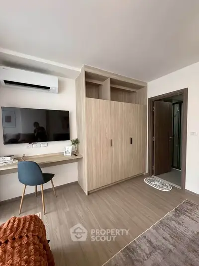 Modern bedroom with built-in wardrobe, wall-mounted TV, and stylish desk setup.