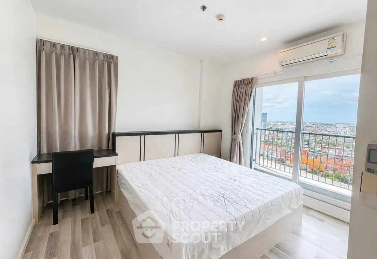 Bright bedroom with balcony and city view, featuring modern furniture and air conditioning.
