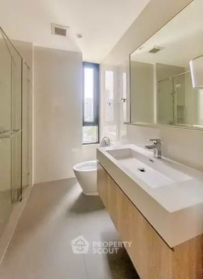 Modern bathroom with sleek fixtures and large mirror in a bright apartment.