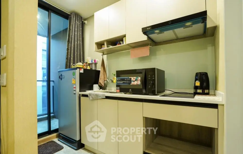 Modern kitchen with sleek appliances and balcony access in urban apartment