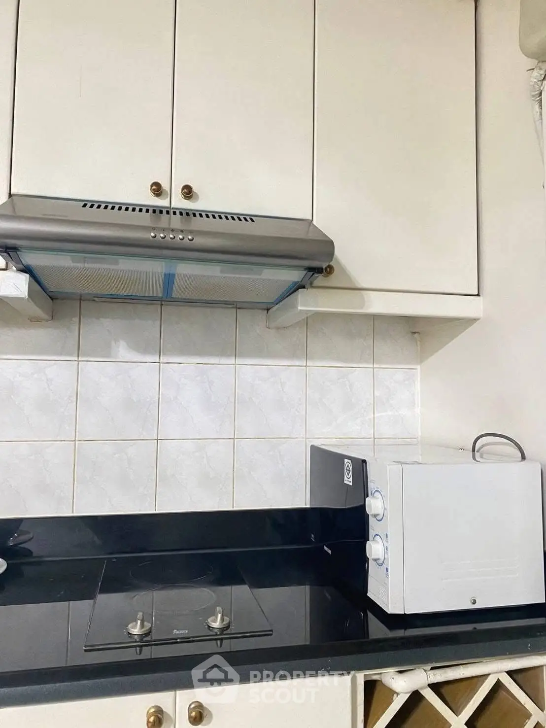 Modern kitchen with sleek black countertop, built-in stove, and white cabinetry for a stylish cooking space.