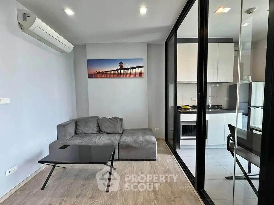 Modern living room with sleek glass partition and compact kitchen area.