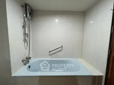 Spacious bathroom with built-in bathtub and modern shower fixtures.