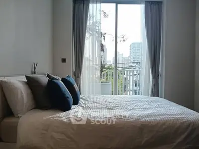 Bright bedroom with city view and balcony access, featuring cozy bedding and elegant curtains.
