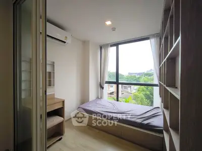 Cozy bedroom with large window and built-in storage overlooking lush greenery.