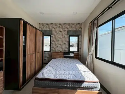 Spacious bedroom with large windows and modern wooden furniture, offering ample natural light and comfort.