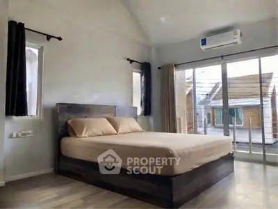 Modern bedroom with large windows and air conditioning, featuring a cozy bed and stylish decor.