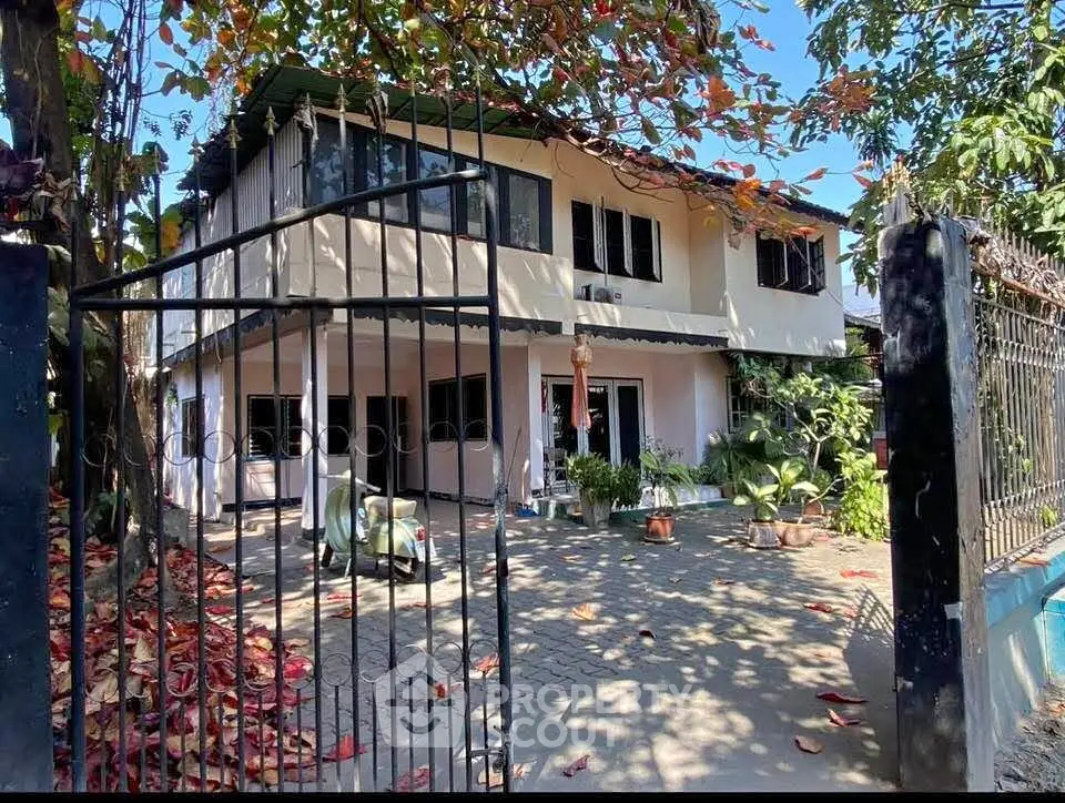 Charming two-story house with spacious front yard and lush greenery, perfect for family living.