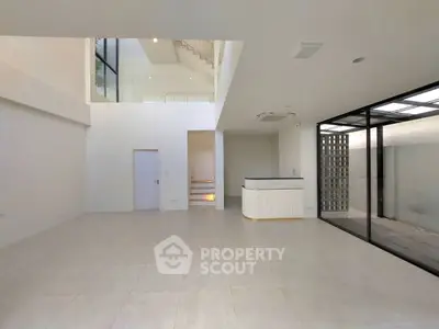 Spacious modern interior with high ceilings and large windows in a minimalist design.