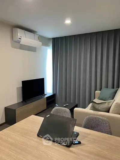 Modern living room with sleek furniture and natural light, featuring a cozy sofa and entertainment setup.