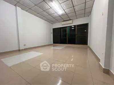Spacious empty room with tiled floor and large windows, ideal for customization.
